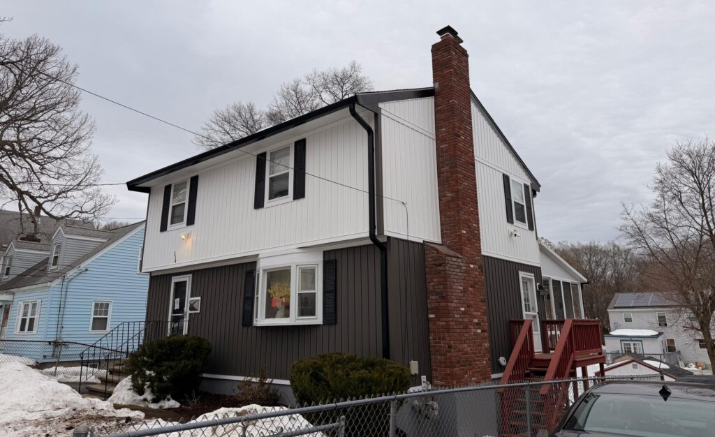 Finished two-tone board and batten siding installation in white and charcoal gray by Titanium Painting & Renovation.
